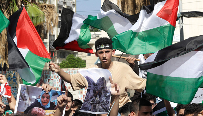 Lebanese and Palestinian students wave flags and hold posters in solidarity with the Palestinians in the Gaza Strip, as they rally in Martyrs Square in southern Lebanon on October 26, 2023. — AFP