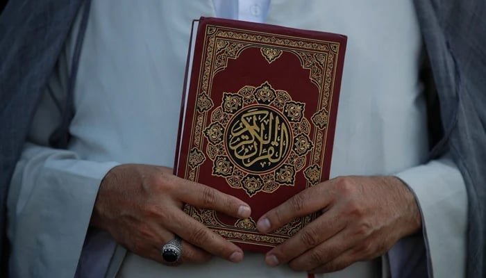A cleric holds the Holy Quran in Baghdad, Iraq, June 30, 2023. — AFP