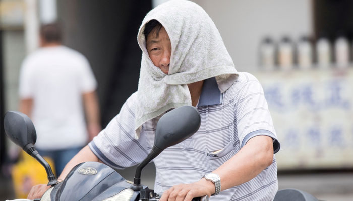 Man seen covering his head with a towel under extreme heat in Beijing. — The Peninsula