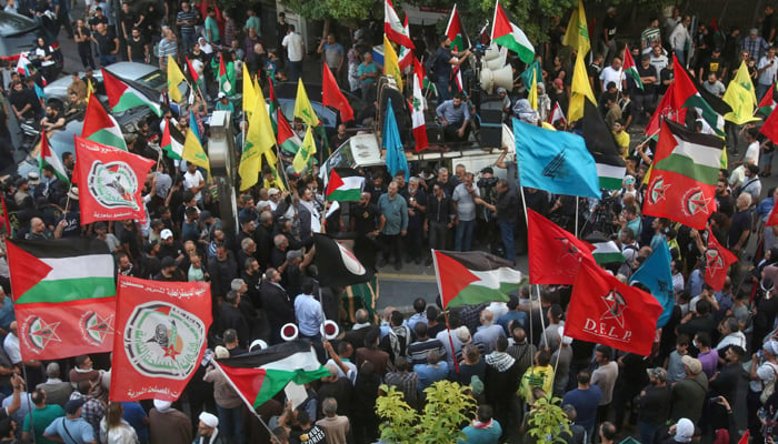 Supporters of Hezbollah and allied Palestinian factions in Lebanon lift flags and placards during a protest in the southern city of Sidon in solidarity with Palestinians in Gaza, on October 28, 2023. — AFP