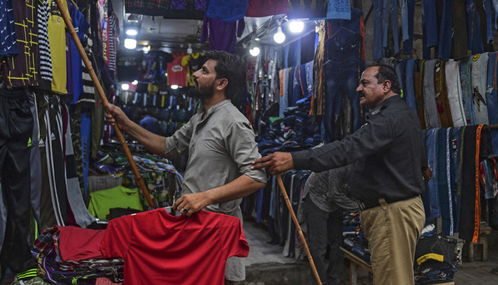 A policeman orders a shopkeeper to close his shop in Karachi. — AFP/File
