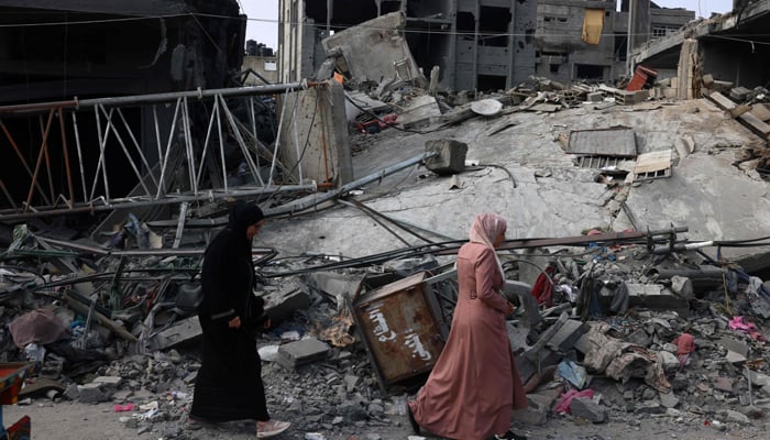 Women walk past a destroyed building in the aftermath of the Israeli bombing in Rafah in the southern Gaza Strip on October 28, 2023. — AFP