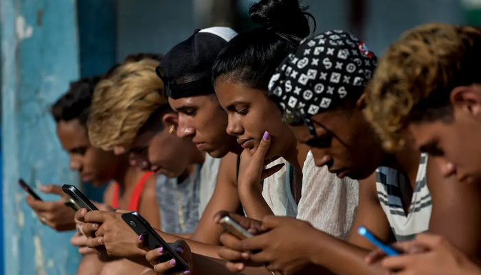 A representational image shows teenagers using their phones. — AFP/File