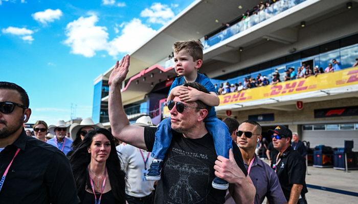 SpaceX CEO Elon Musk with one of his sons walks on the pit lane after the 2023 United States Formula One Grand Prix at the Circuit of the Americas in Austin, Texas, on October 22, 2023. — AFP
