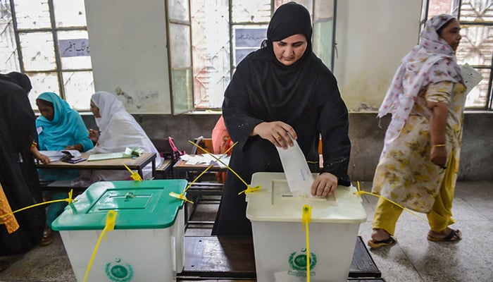 A woman casts her vote during Pakistans general election at a polling station during the general election in Lahore. — AFP/File
