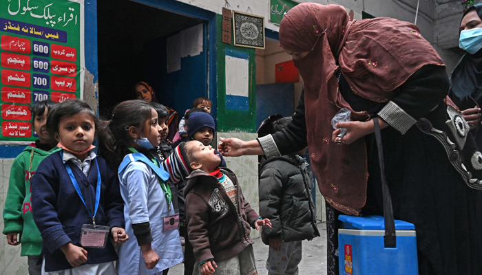 A health worker administers polio vaccine drops to a child at a school during a vaccination campaign in Lahore on January 16, 2023. — AFP