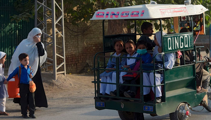 Students ride on a three-wheeler vehicle on way to their school in Peshawar on September 15, 2020. — AFP