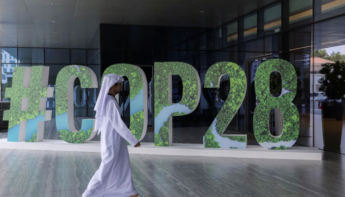 A person walks past a #COP28 sign during The Changemaker Majlis thought leadership workshop in Abu Dhabi, United Arab Emirates on October 1, 2023. — France 24