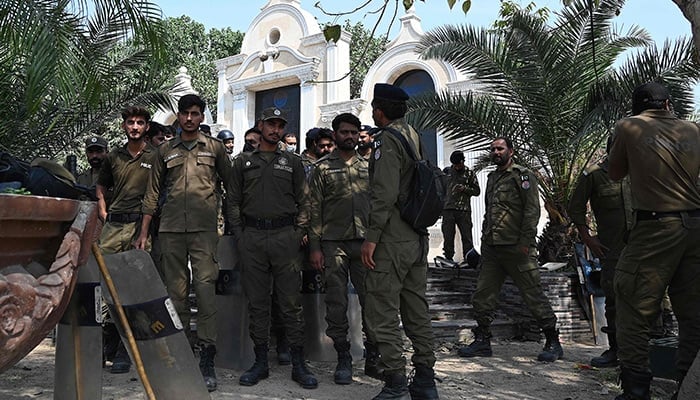 Policemen gather near a street blocked with containers (not pictured) by authorities in Lahore on March 16, 2023. — AFP