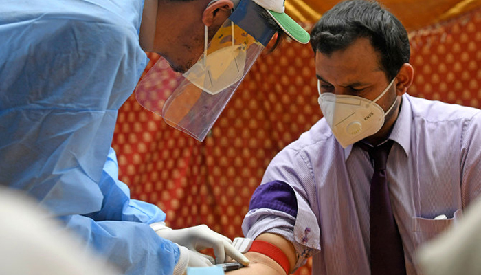 A health official wearing protective gear takes blood sample of a man in Islamabad. — AFP/File