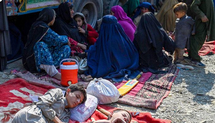 Benafsha and her six children huddle together on a ragged blanket near a truck piled high with their household belongings on the Afghan border with Pakistan. — AFP