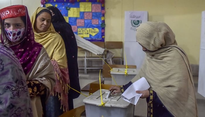 Women stand in a queue inside a polling station during a local body election in Peshawar. — AFP/File