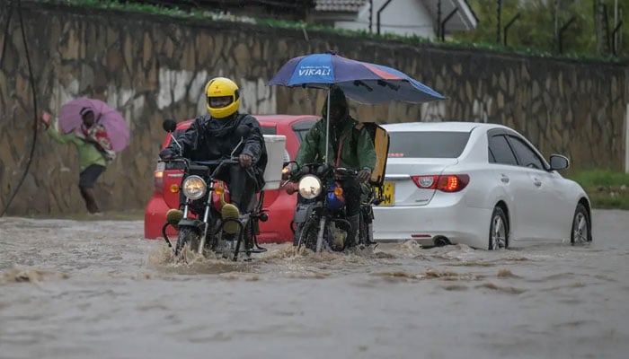 Motorbike riders wade through a waterlogged street after heavy rains in Mombasa on November 3, 2023. — AFP