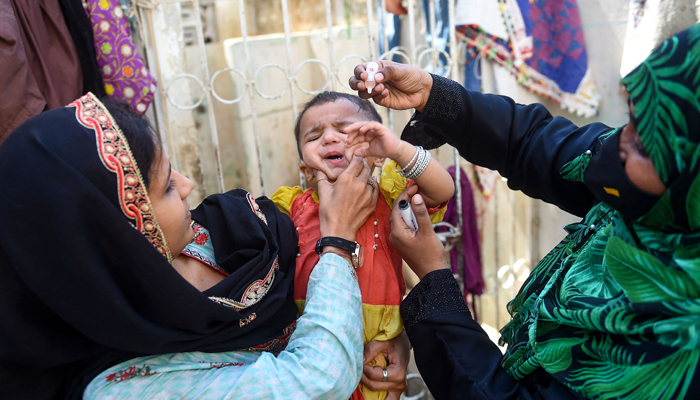 A health worker administers polio drops to a child during a door-to-door vaccination campaign on October 2, 2023. — AFP