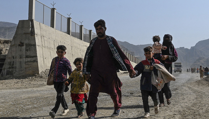 An Afghan refugee family arrives on foot to cross the Pakistan-Afghanistan Torkham border on November 2, 2023. — AFP