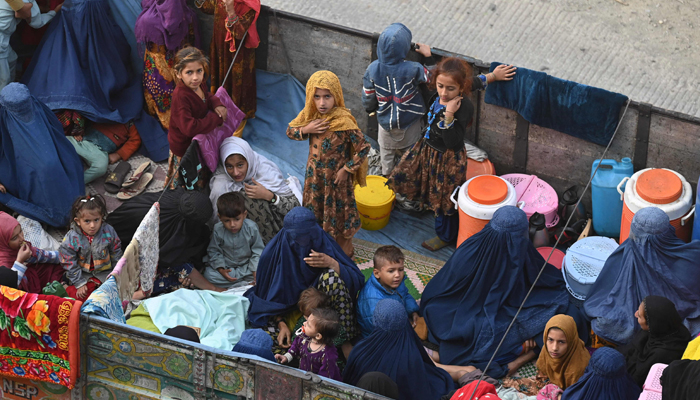 Afghan refugee families sit on a truck heading towards the Pakistan-Afghanistan Torkham border on November 3, 2023. — AFP