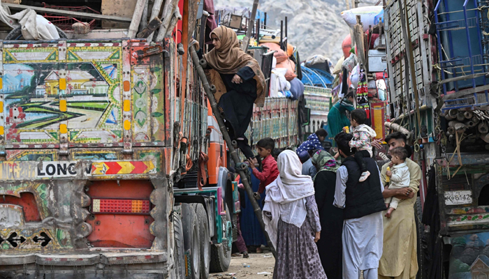 Afghan refugees climb a truck as they prepare to depart for Afghanistan, at a holding centre in Landi Kotal, on November 1, 2023. — AFP