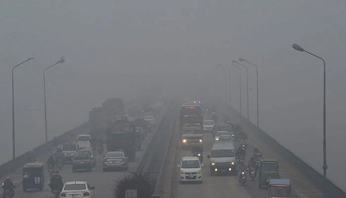 Commuters on a road in Lahore amid thick smog. — AFP/File