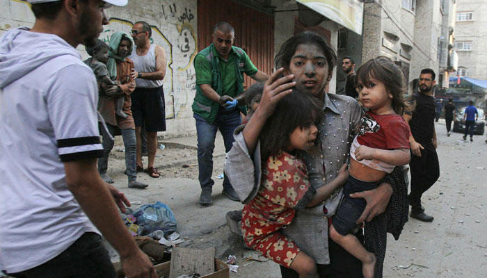 A Palestinian girl holds two children as she stands on a street in Gaza City on October 12, 2023 as Israeli airstrikes on the enclave continued.—AFP