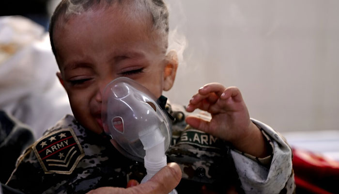 A boy with breathing difficulties reacts as his mother helps him use a nebuliser in a crowded New Delhi hospital.— AFP File