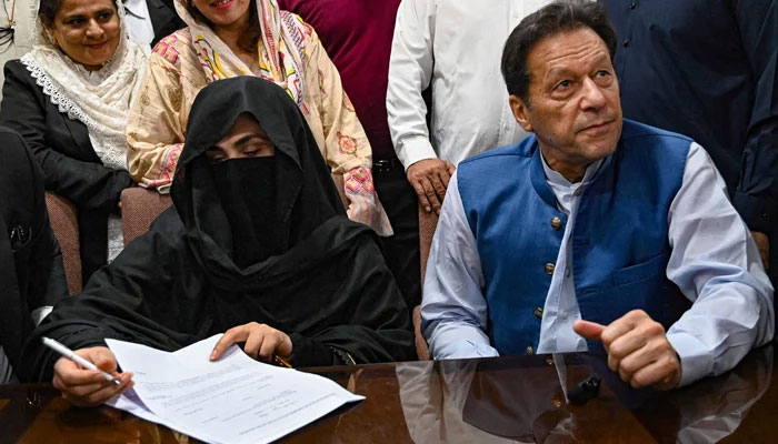 Former Prime Minister, Imran Khan (left) along with his wife Bushra Bibi signs surety bonds for bail in various cases, at a registrars office in the High Court, in Lahore on July 17, 2023. — AFP