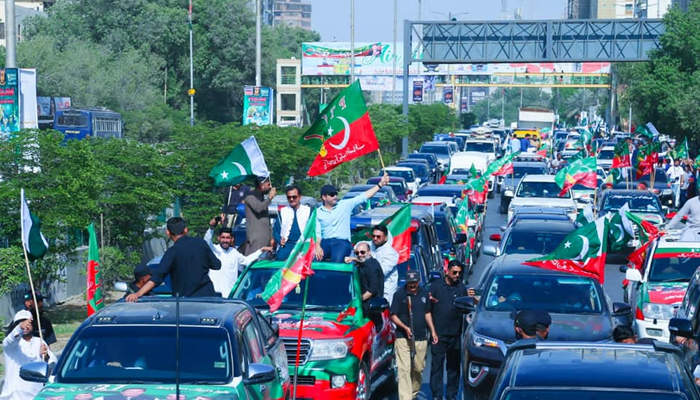 Pakistan Tehreek-e-Insaf workers during a party rally wave flags in this image released on March 23, 2022. — Facebook/Khurrum Sher Zaman
