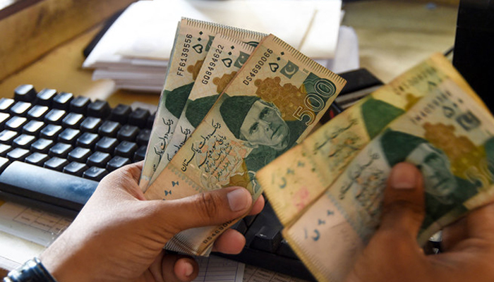 A man counts Pakistans rupees at his shop in Karachi. — AFP/File