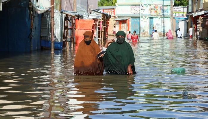 Women can be seen walking in the flood water in Somalia. — AFP