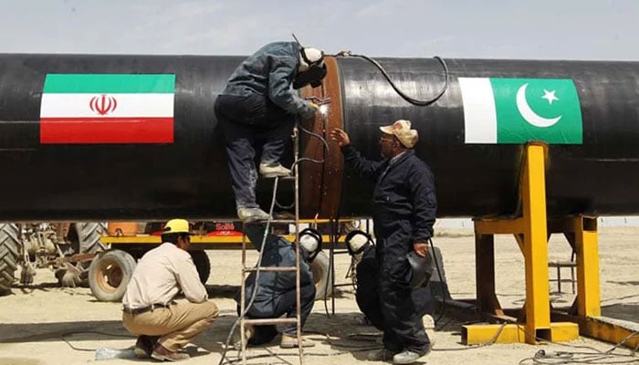 Iranians work on a section of a pipeline linking Iran and Pakistan after the project was launched during a ceremony in the Iranian border city of Chah Bahar. — AFP