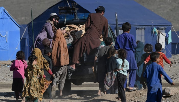 Afghan refugees children run to receive bread from a local charity at a makeshift camp upon their arrival from Pakistan, near the Torkham border in Nangarhar province on November 12, 2023. — AFP