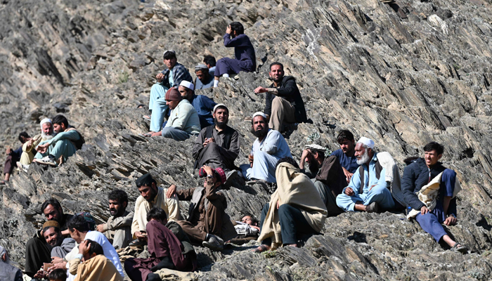 Afghan refugees sit on a hilltop outside the IOM office as they wait for registration upon their arrival from Pakistan near the Torkham border in Nangarhar province on November 12, 2023. — AFP