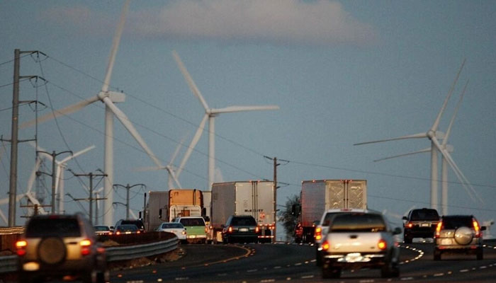 Emissions-producing diesel trucks and cars pass non-polluting windmills along the 10 freeway near Banning, California. — AFP File