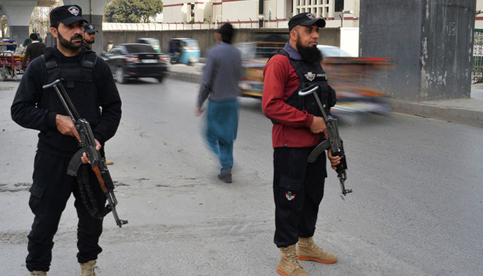 Peshawar police officials stand guard on a busy road in KP. — AFP/File