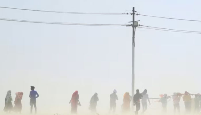 People walk through a dust storm on a hot summer day in India in April 2023.  —AFP File
