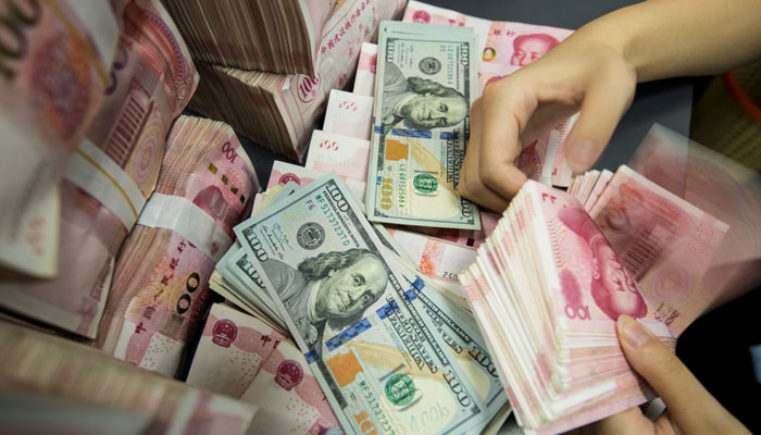 A Chinese bank employee counts 100-yuan notes and U.S. dollar bills at a bank counter in Nantong, China, on Aug. 28, 2019.— AFP