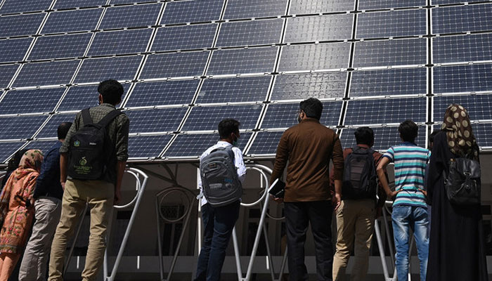 Students look at the facade of a building made with solar panels producing some 148 Kilowatts during its inauguration at the University of Engineering and Technology in Lahore on October 12, 2020. — AFP/File