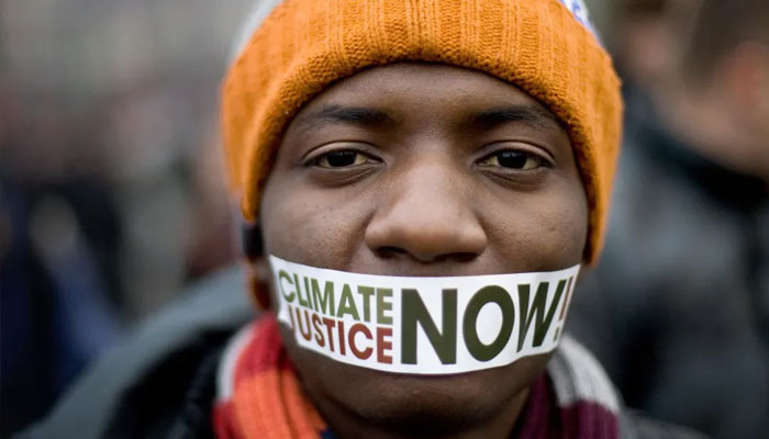 A protestor wears a sticker on his mouth reading Climate Justice Now in front of a demonstration against climate change in central Poznan during the UN Climate Change Conference on December 6, 2008. — AFP File