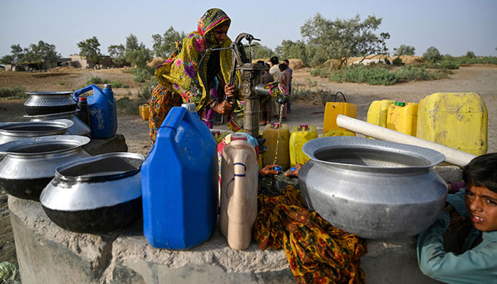 In this picture taken on May 11, 2022, a woman fills cans with water from a hand pump during a heatwave in Jacobabad, in the southern Sindh province. —AFP