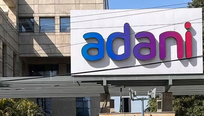 Employees walk past the Adani House corporate building at the institutional area in Gurugram on February 8, 2023.—AFP