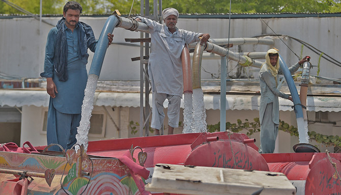 Workers supervise as a water tanker is filled from a hydrant, to supply at residential areas for a charge on the outskirts of Islamabad. — AFP/File