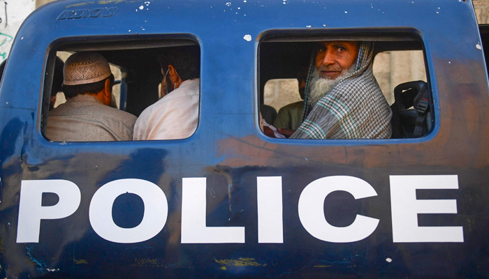 Detained Afghan refugees sit in a van during a search operation to identify alleged illegal immigrants, on the outskirts of Karachi on November 17, 2023. — AFP