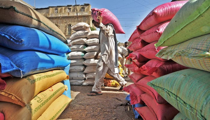 A worker can be seen carrying a sugar bag from a place filled with numerous sugar bags. — AFP/File