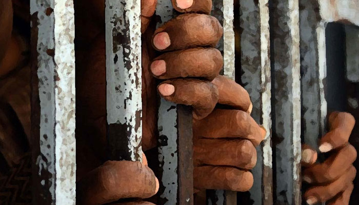 Representational image shows the hands of prisoners held behind bars. — AFP/File