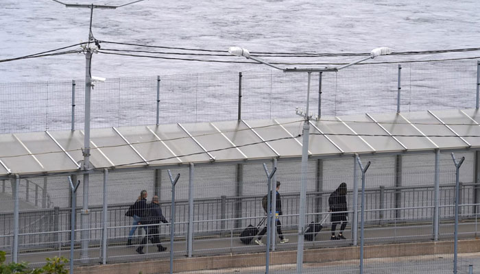 People walk on the bridge over the Narva River at the border crossing point with Russia in Narva, Estonia. — AFP File