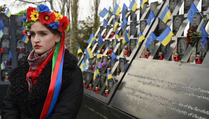 A Ukrainian woman stands next to a memorial for those killed during the Maidan protests. — AFP File