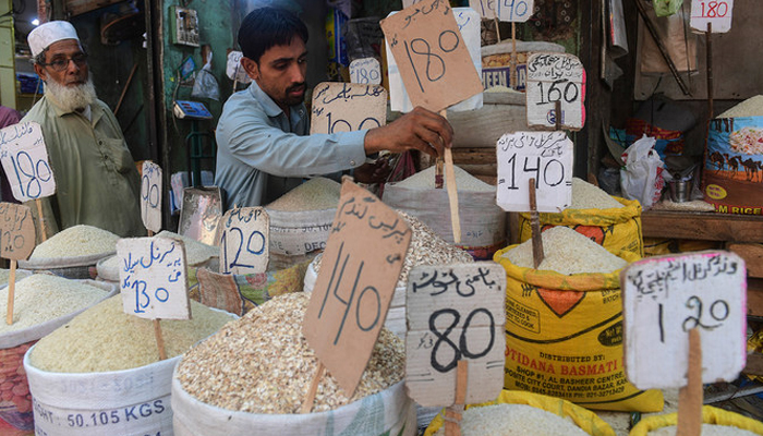 A shopkeeper places a price tag on rice at a shop in Karachi. — AFP/File