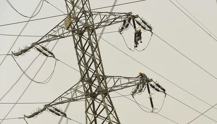 Technicians of the Karachi Electric Corporation work on a high-voltage line in Karachi. — AFP/File