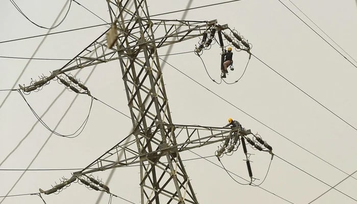 Technicians of the Karachi Electric Corporation work on a high-voltage line in Karachi. — AFP/File