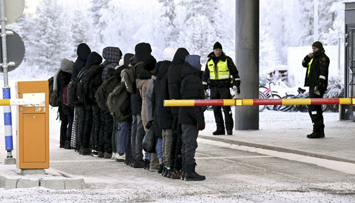 Asylum seekers who have crossed the border from Russia to Finland stand at the fishing border crossing in Salla on 22 November. — AFP File