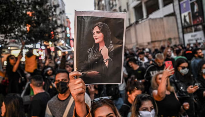 A protester holds a portrait of Mahsa Amini during a demonstration in support of Amini, a young Iranian woman who died after being arrested in Tehran by the Islamic Republics morality police, on Istiklal avenue in Istanbul on 20 September, 2022.  — AFP